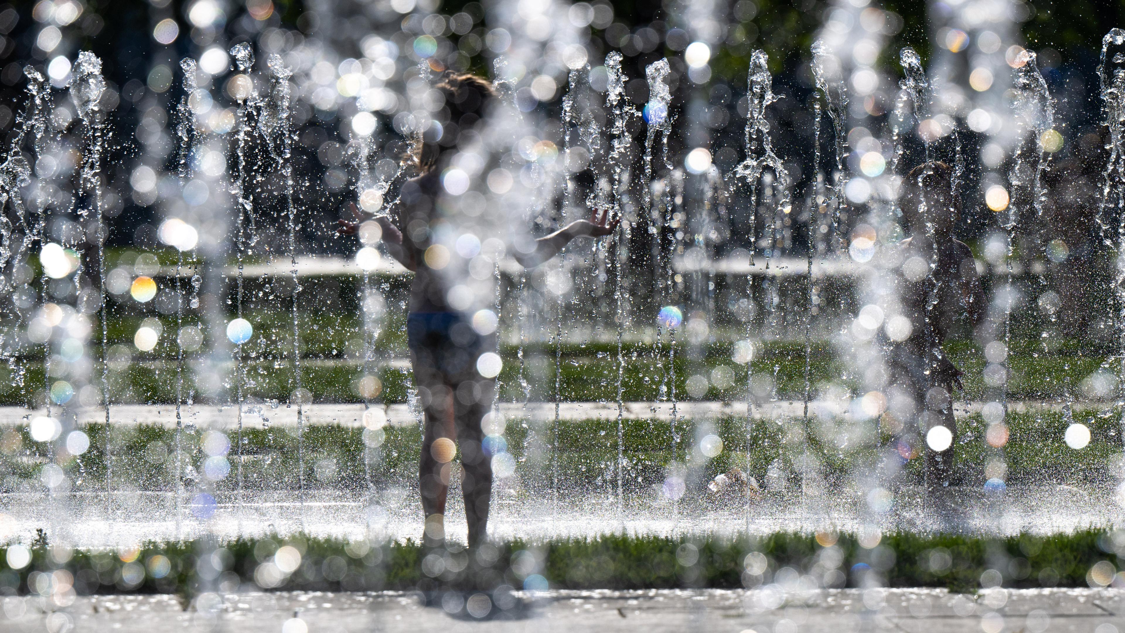 Berlin: Kinder spielen bei sommerlichen Temperaturen am Springbrunnen vor dem Kanzleramt.