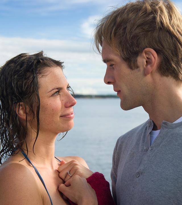 Britta Ingerson (Anna Rot) und Bertil Hanson (Mathis Landwehr) stehen sich vor dem See eng gegenüber und schauen sich in die Augen.