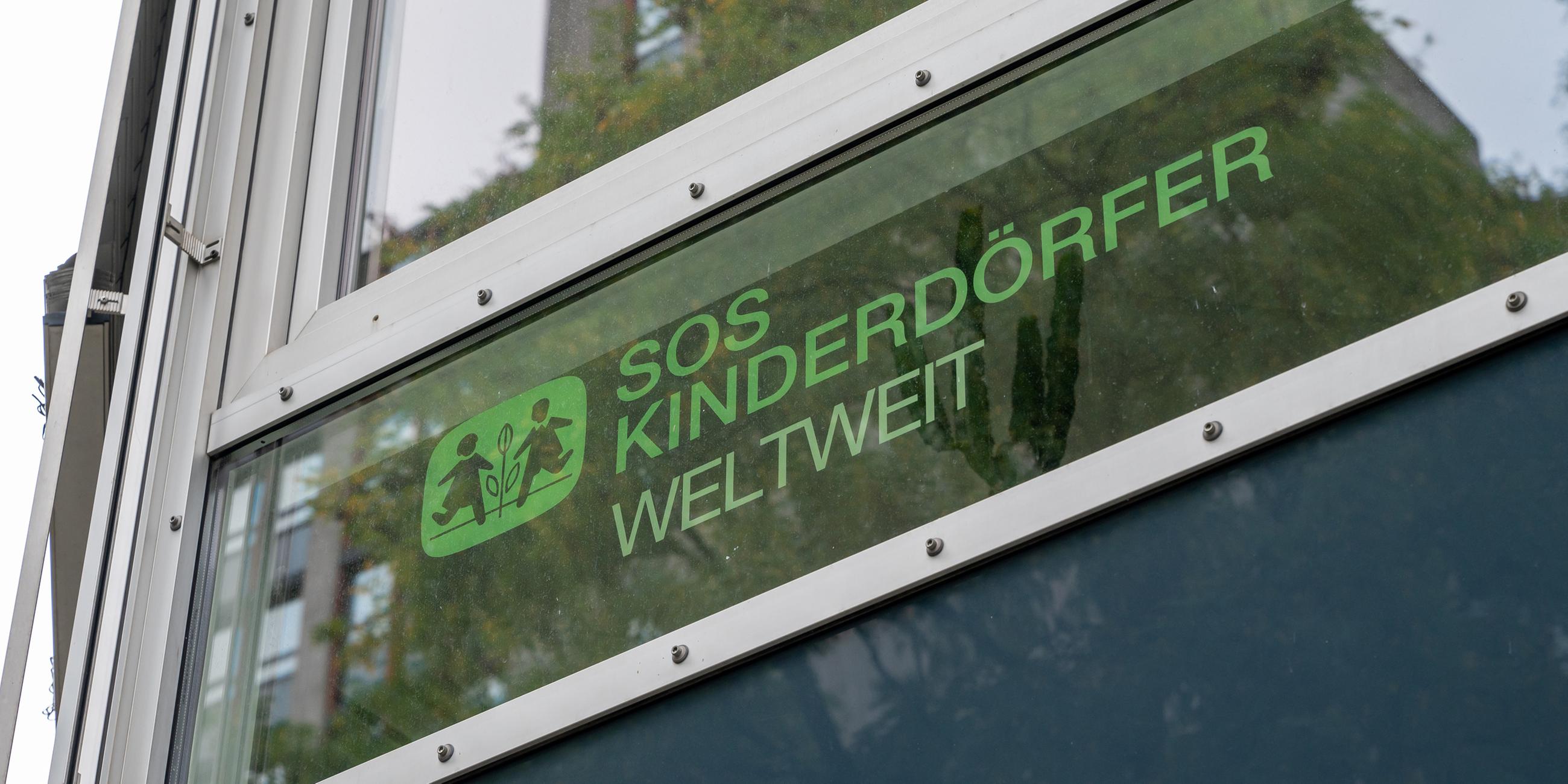 Der Schriftzug „SOS Kinderdörfer - Weltweit“ steht an einem Fenster.