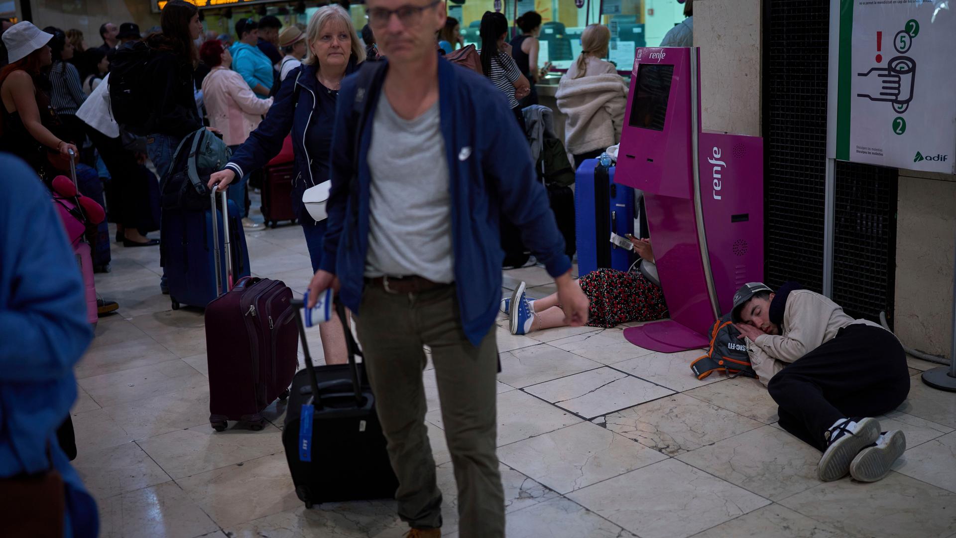 Spanien, Barcelona: Fahrgäste drängen sich in den Zugängen, während andere am Boden des Bahnhofs Sants in Barcelona, Spanien, schlafen.
