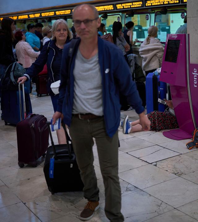 Spanien, Barcelona: Fahrgäste drängen sich in den Zugängen, während andere am Boden des Bahnhofs Sants in Barcelona, Spanien, schlafen.