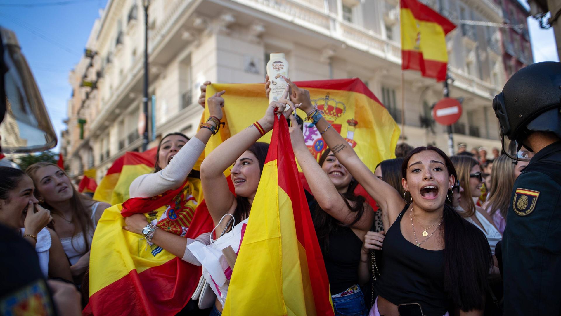 Menschen halten spanische Flaggen hoch und skandieren Parolen.