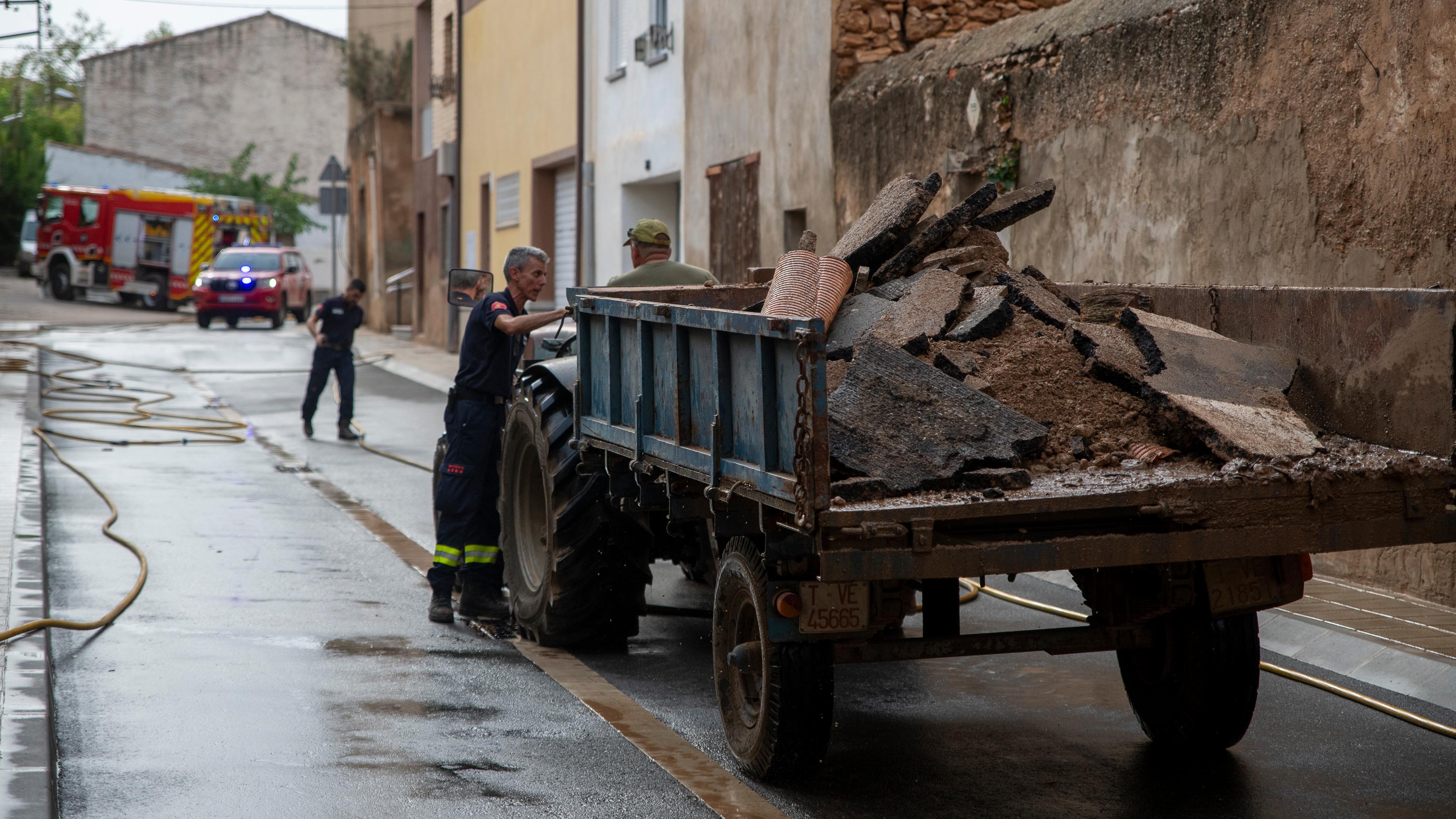 Zwei Männer sammeln Trümmer nach den Unwettern in Katalonien ein.