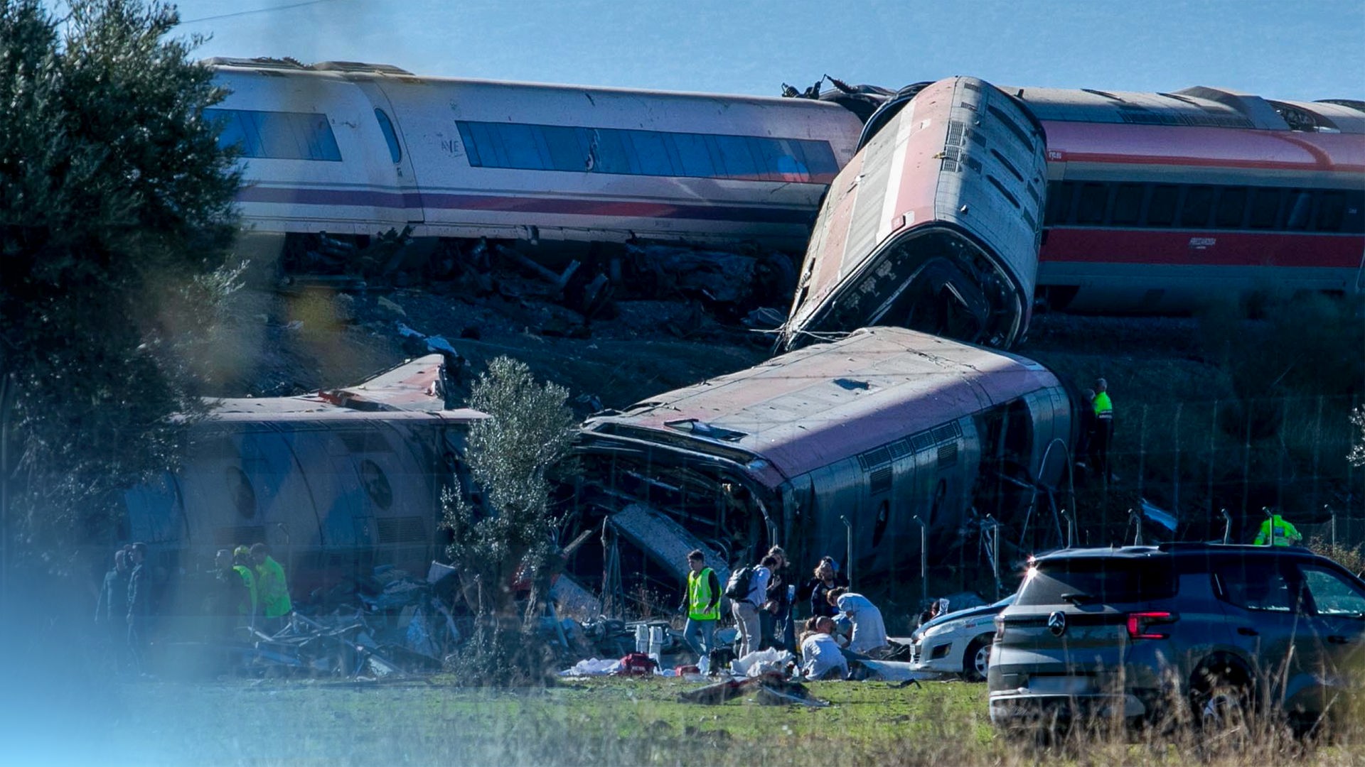 Verunglückte Wagons nach der Kollision zwei spanischer Züge, Teile eines Wagons hängen einen Hang hinunter und sind zerstört, Rettungskräfte sind an der Unfallstelle.