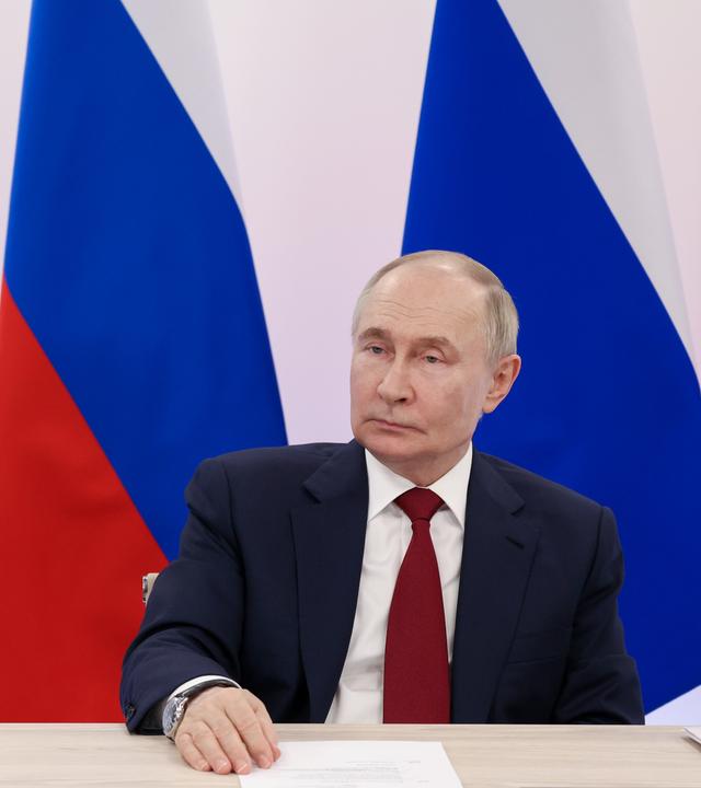 Putin ist vor einer Karte der Ukraine zu sehen. 