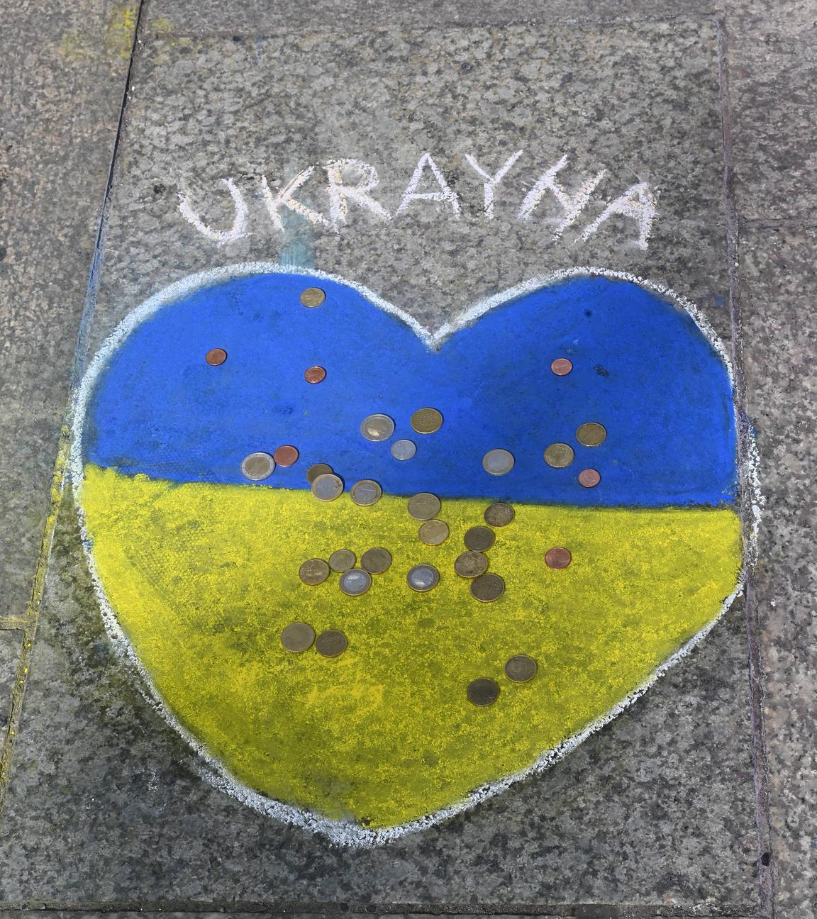 Mit einem Herz in den Farben der Ukraine auf dem Gehweg werden Geldspenden gesammelt 