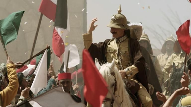 Spielszene: Kaiser Wilhelm der II. reitet durch eine Menge arabischer Menschen