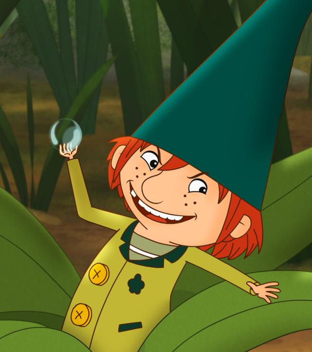 Der Wichtel Nisse sitzt im Gras und heckt schon wieder etwas Schelmisches aus.