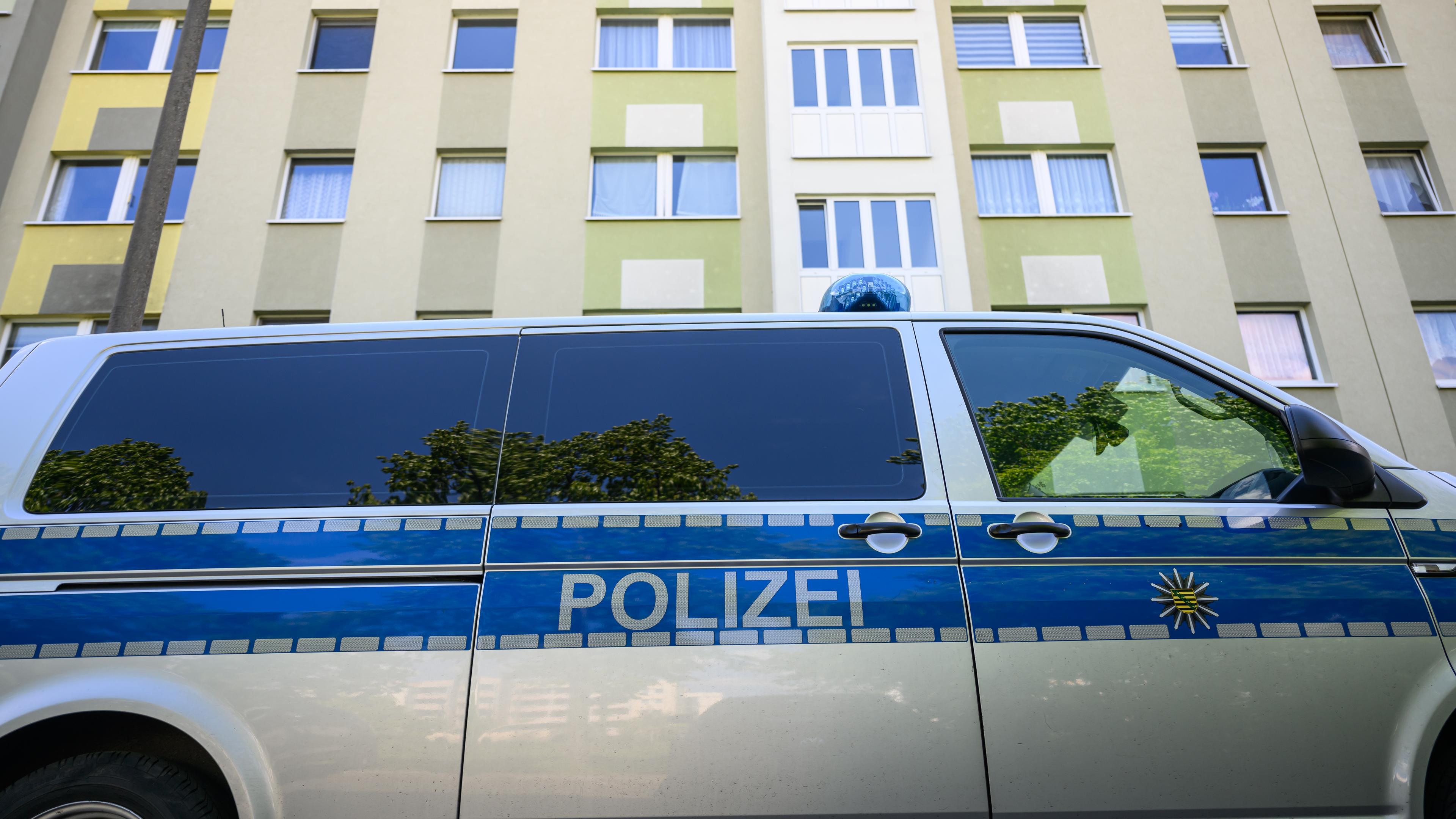 Ein Polizeiauto steht vor einem Wohnhaus. Ein Mitarbeiter des deutschen Europaabgeordneten Krah ist in Dresden wegen des Verdachts der Spionage für China festgenommen worden.