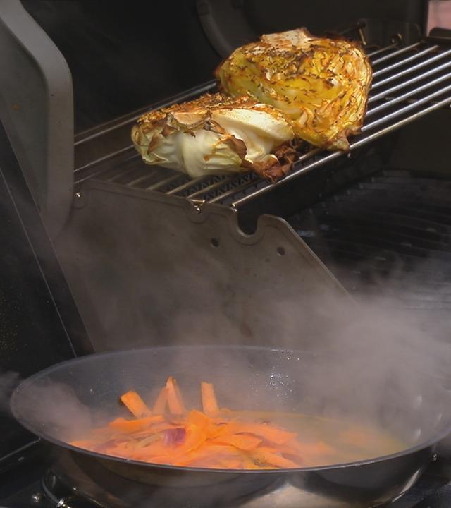 Grillgemüse auf einem Grill und Möhren in einer Pfanne.