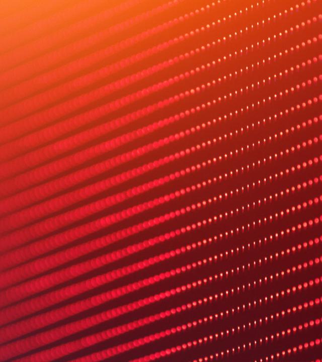 Ein abstraktes Muster aus roten und orangefarbenen Punkten verläuft in diagonalen Reihen über das Bild. Die Darstellung erinnert an digitale Displays oder LED-Strukturen.