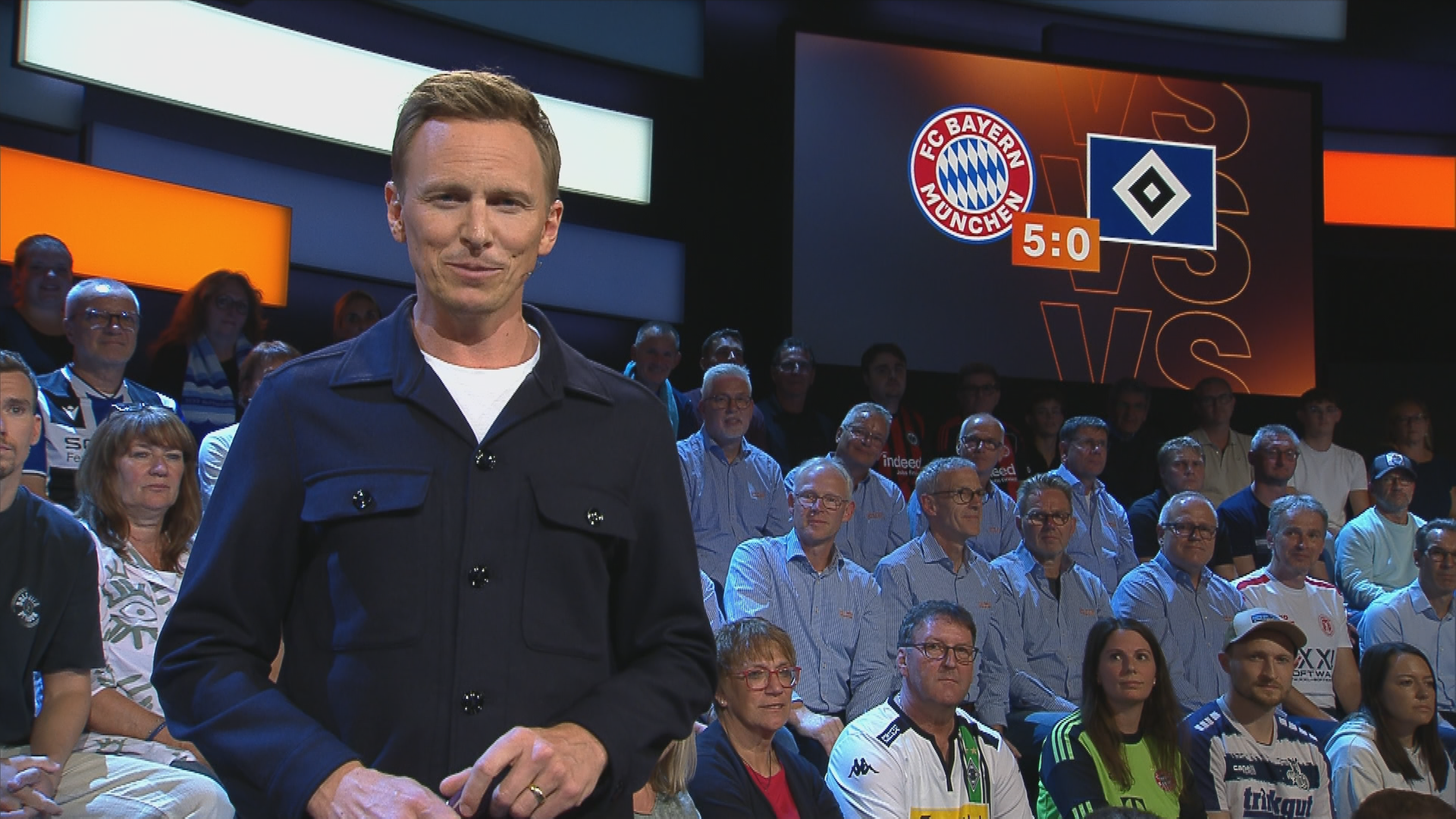 Jochen Breyer steht vor dem "sportstudio"-Publikum und schaut in die Kamera.