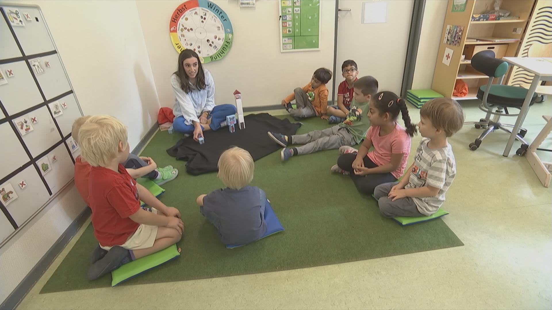 Fachkraft für Sprachförderung arbeitet mit Kindern im Sitzkreis.