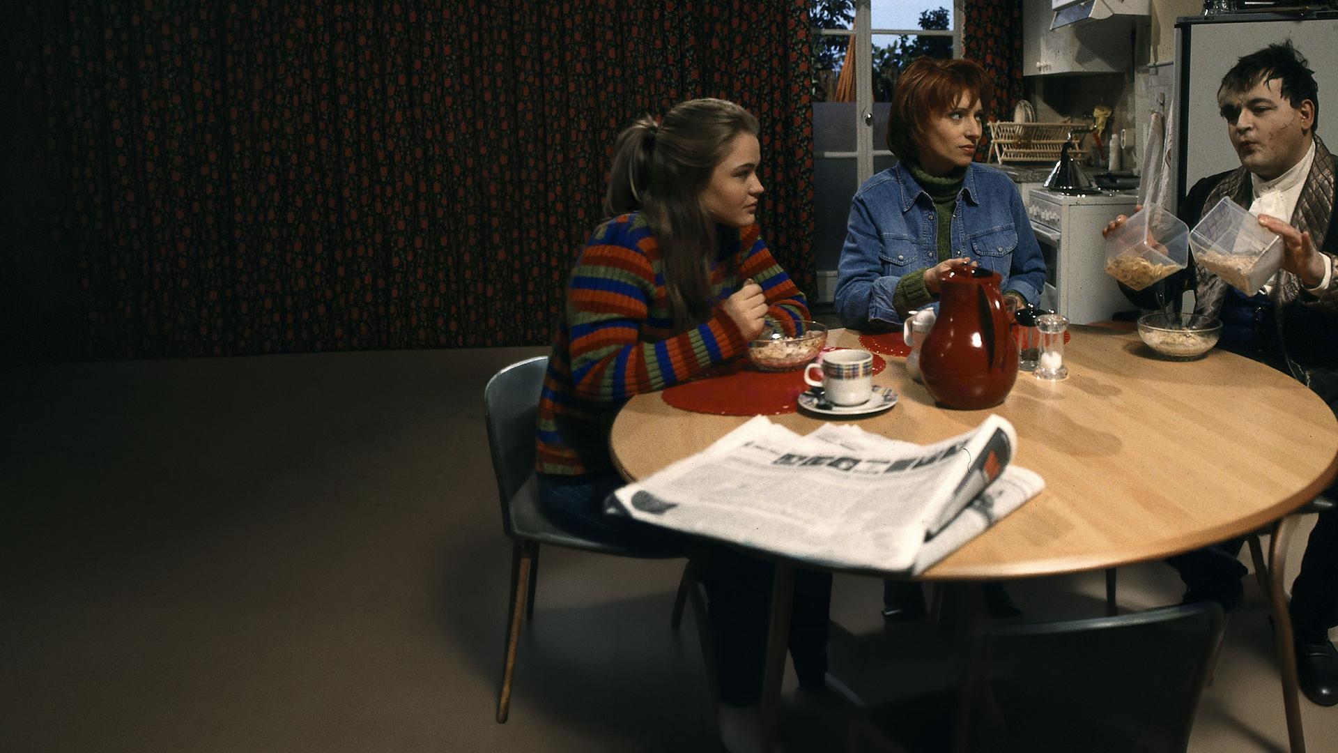 "Sprechstunde bei Dr. Frankenstein": Franzi (Floriane Eichhorn), Charly (Silke Matthias) und Lenni ((Michael Trischan) sitzen beim Frühstück an einem runden Tisch in der Küche.