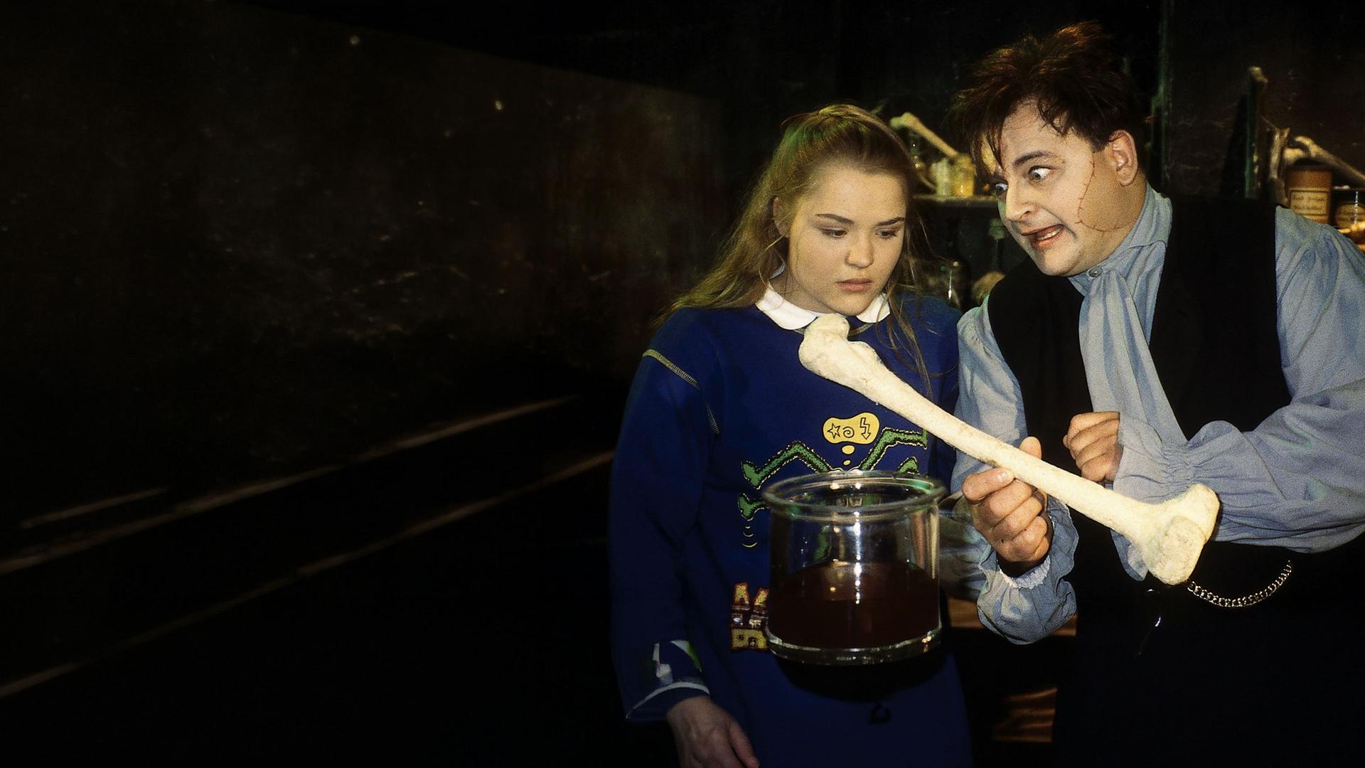 "Sprechstunde bei Dr. Frankenstein": Lenni (Michael Trischan) demonstriert Franzi (Fritzi Eichhorn) ein neues Experiment. Er hält einen großen Knochen in der Hand, auf den Franzi schaut.