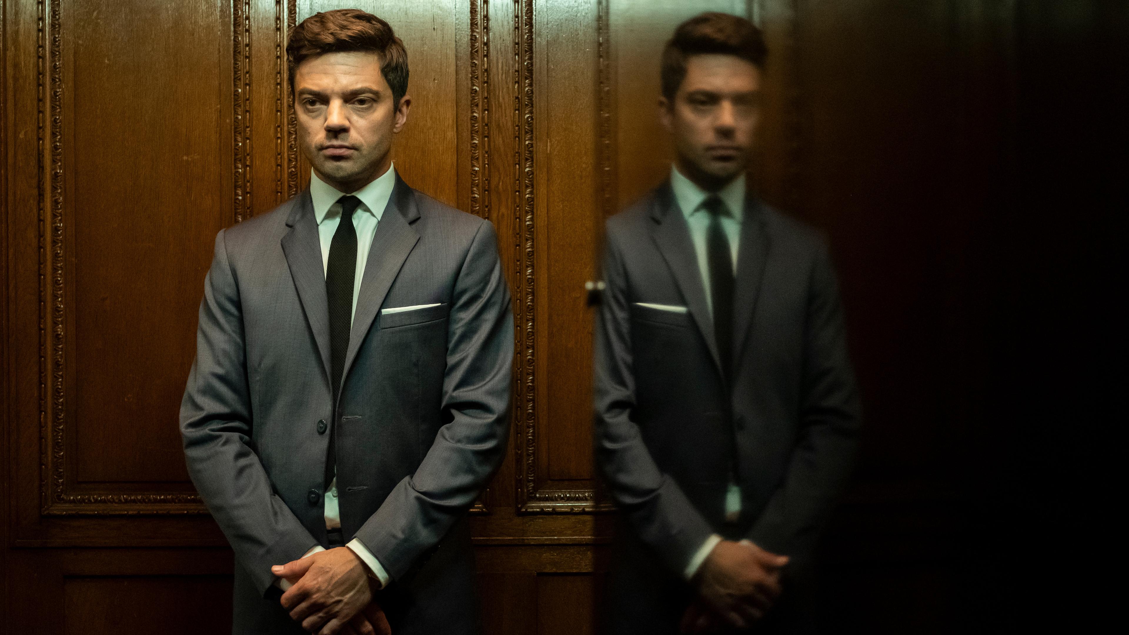 "Spy City (1)": Fielding Scott (Dominic Cooper) in einem Holzvertäfelten Aufzug stehend.