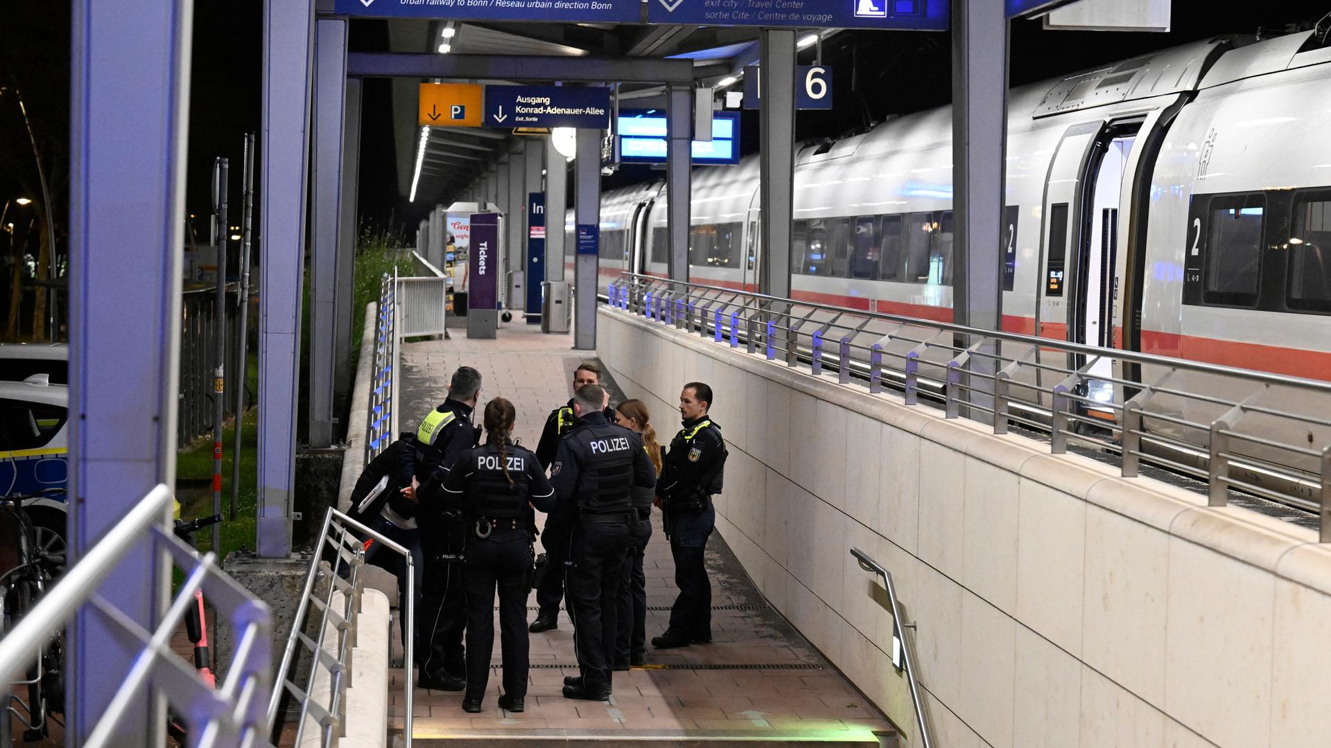 03.04.2026, Nordrhein-Westfalen, Siegburg: Polizisten stehen auf einem Bahnsteig im Bahnhof Siegburg, auf dem ein ICE der Deutschen Bahn steht.