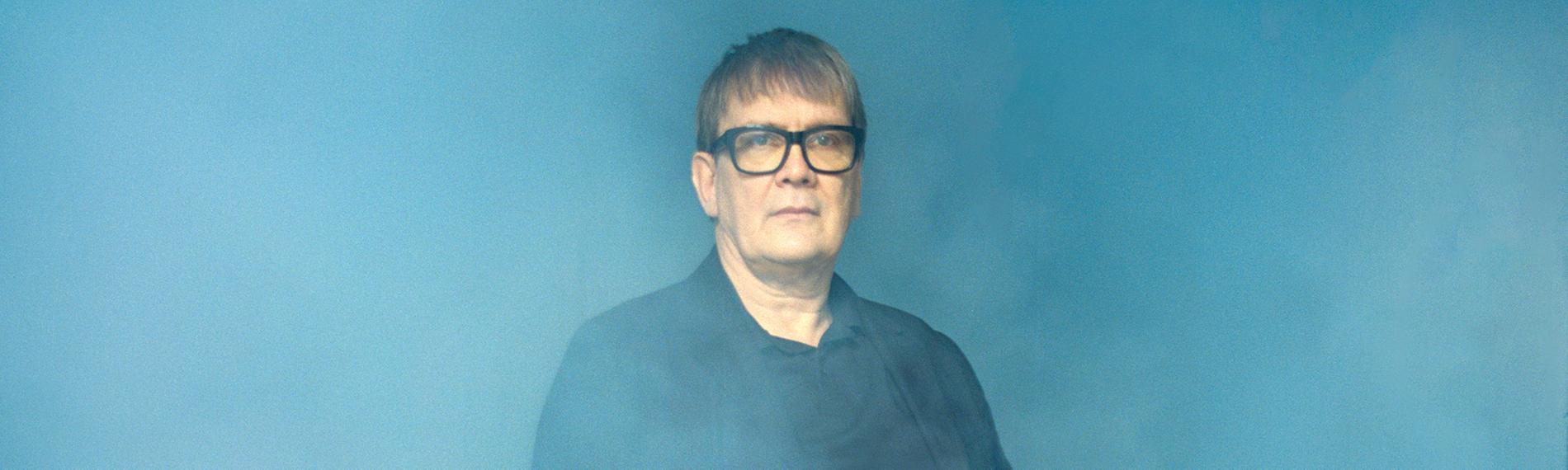 Der Mainzer Stadtschreiber 2026 Seven Regener sitzt auf einem Stuhl in nebliger Umgebung