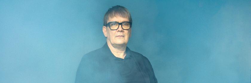 Der Mainzer Stadtschreiber 2026 Seven Regener sitzt auf einem Stuhl in nebliger Umgebung