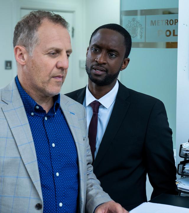 "The Chelsea Detective - Spiel auf Leben und Tod": Connor (Peter Bankolé) steht neben Ricky (Nigel Lindsay) und spricht ihn an. Im Hintergrund ein Treppenhaus.