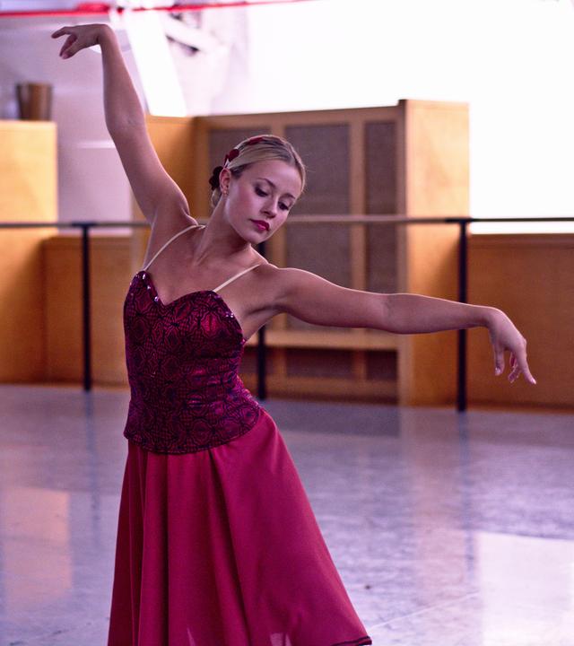 Lena (mittig) tanz in einem roten Kleid.