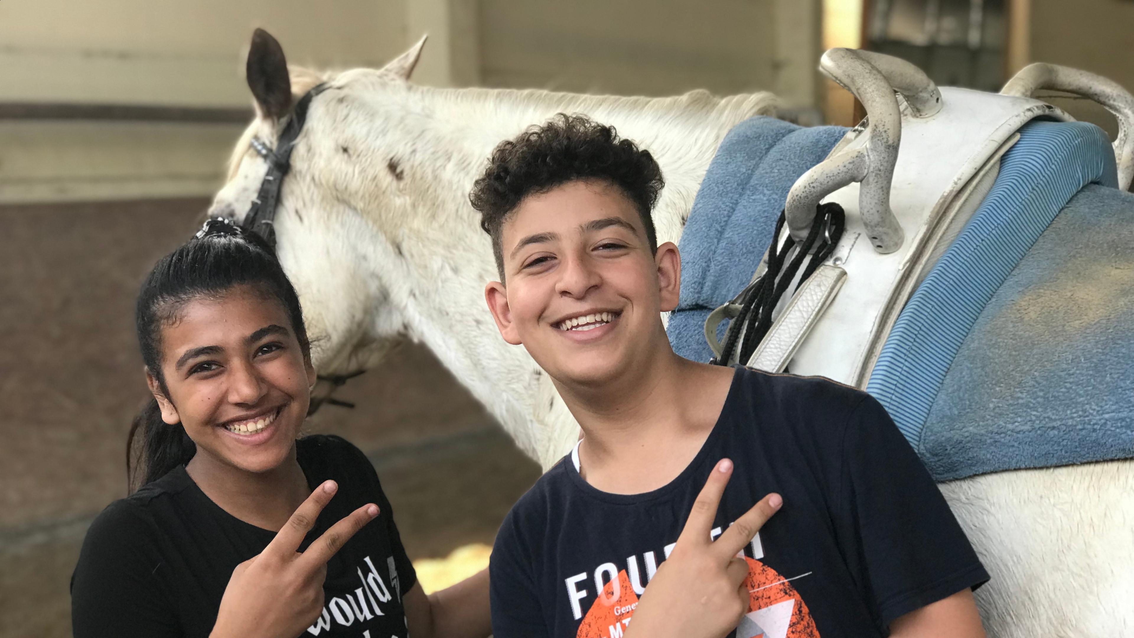Nabaa und Hassan vor einem weißen Pferd