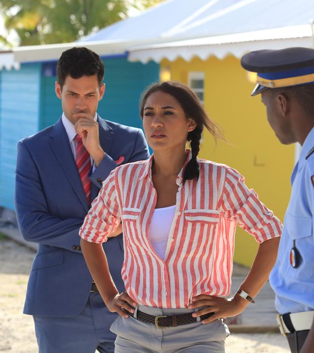 "Death in  Paradise - Die tote Braut": Florence Cassell (Josephine Jobert) steht zwischen Dwayne (Danny John-Jules), Oliver (Stefano Braschi) und J.P. (Tobi Bakare) und schaut in die Ferne.