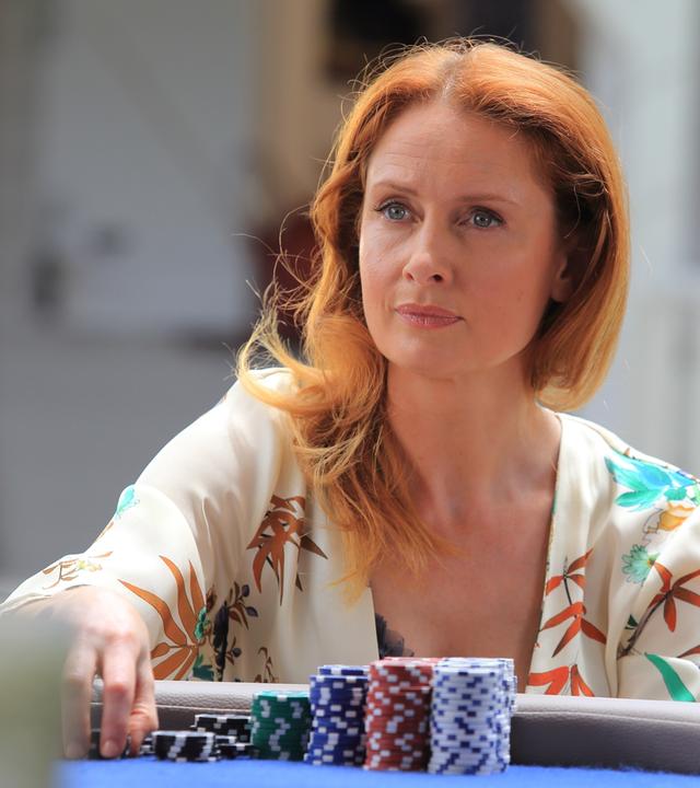 "Death in Paradise - Das letzte Spiel": Melanie Devaux (Zoe Telford) sitzt am Pokertisch hinter einem Stapel Pokerchips.