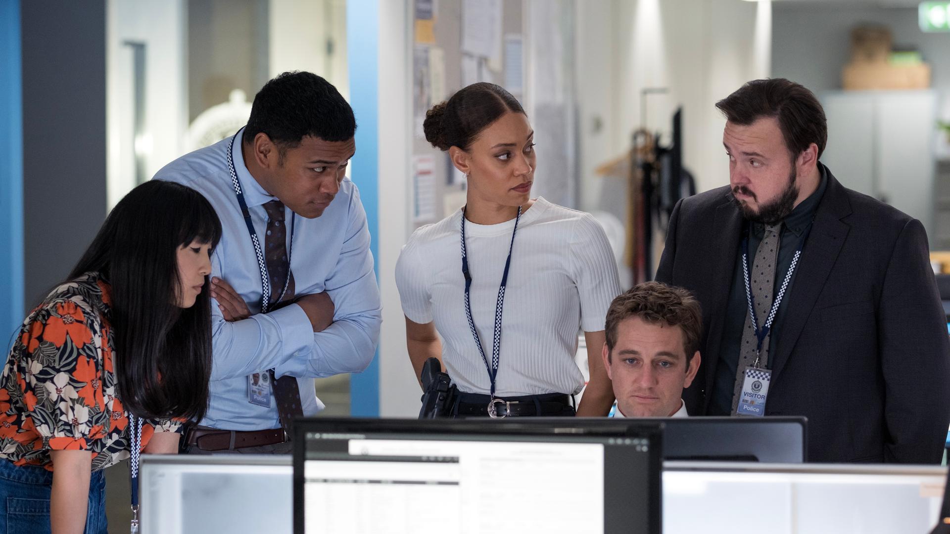 "North Shore – Tod in Sydney – Termingeschäfte": DC Lachie Hooper (Dylan Hare) sitzt an seinem Schreibtisch vor einem Computerbildschirm. PC Cindy Yoo (Cassandra Sorrell), DC Paea Leniu (Chris Alosio), DS Meg Driscoll (Kirsty Sturgess) und DS Max Drummond (John Bradley) stehen um ihn herum.