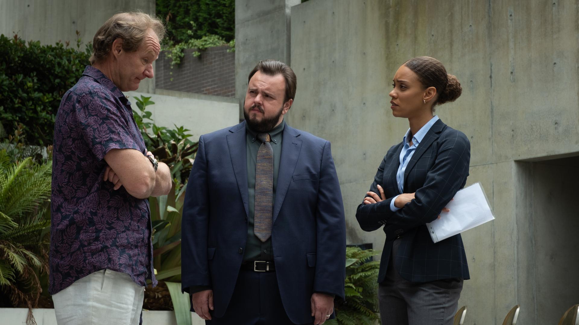 "North Shore – Tod in Sydney – Termingeschäfte": Max (John Bradley) und Meg (Kirsty Sturgess) stehen mit Lloyd (Rob Carlton) vor einem Gebäude. Sie schauen ihn an. Er hat die Arme vor dem Körper verschränkt und blickt leicht nach unten.