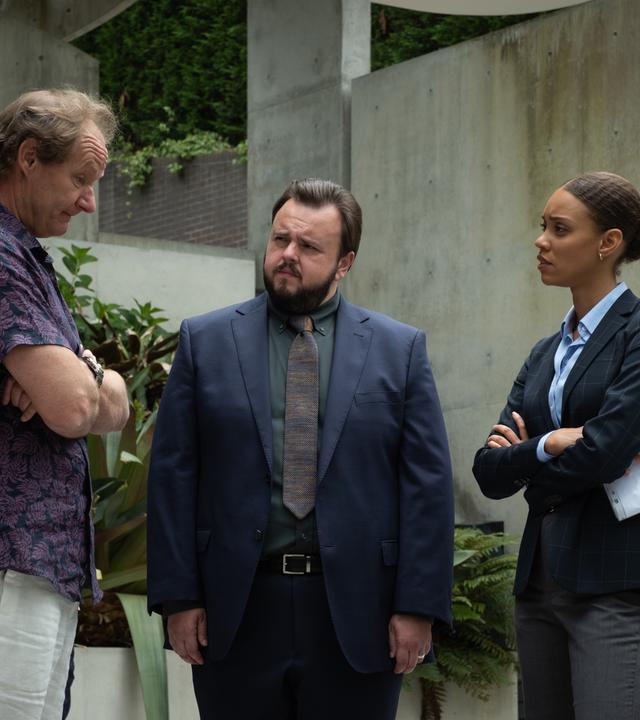 "North Shore – Tod in Sydney – Termingeschäfte": Max (John Bradley) und Meg (Kirsty Sturgess) stehen mit Lloyd (Rob Carlton) vor einem Gebäude. Sie schauen ihn an. Er hat die Arme vor dem Körper verschränkt und blickt leicht nach unten.