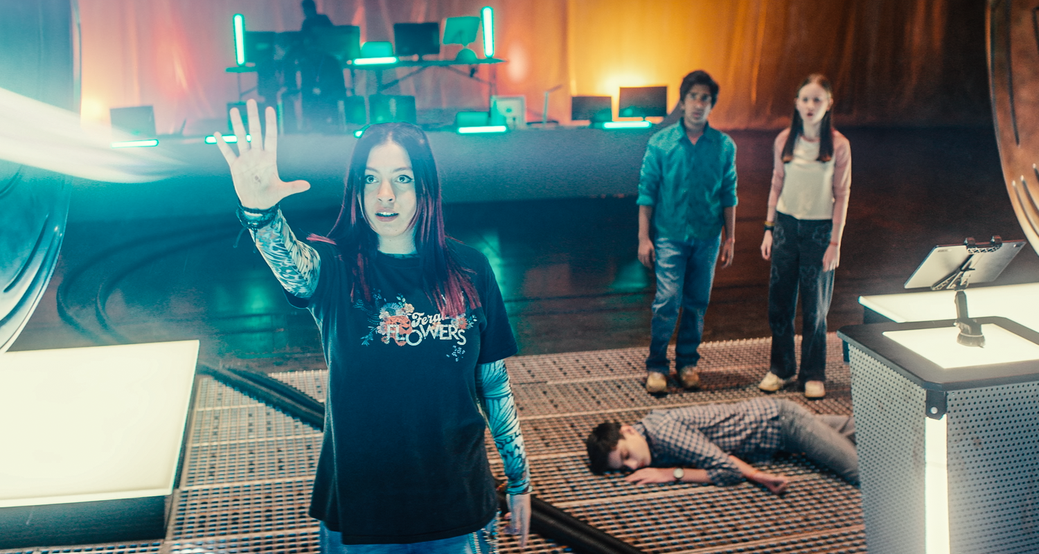 In der großen Halle auf dem Boden bei den Artefakten liegt Louis mit geschlossenen Augen. Bei ihm stehen Glen und Meg und beobachten Kaz. Kaz hat den Arm gehoben und aus ihrer gespreizter Hand kommt ein weißer dicker Lichtstrahl. Kaz schaut konzentriert in Richtung des Lichtstrahls.