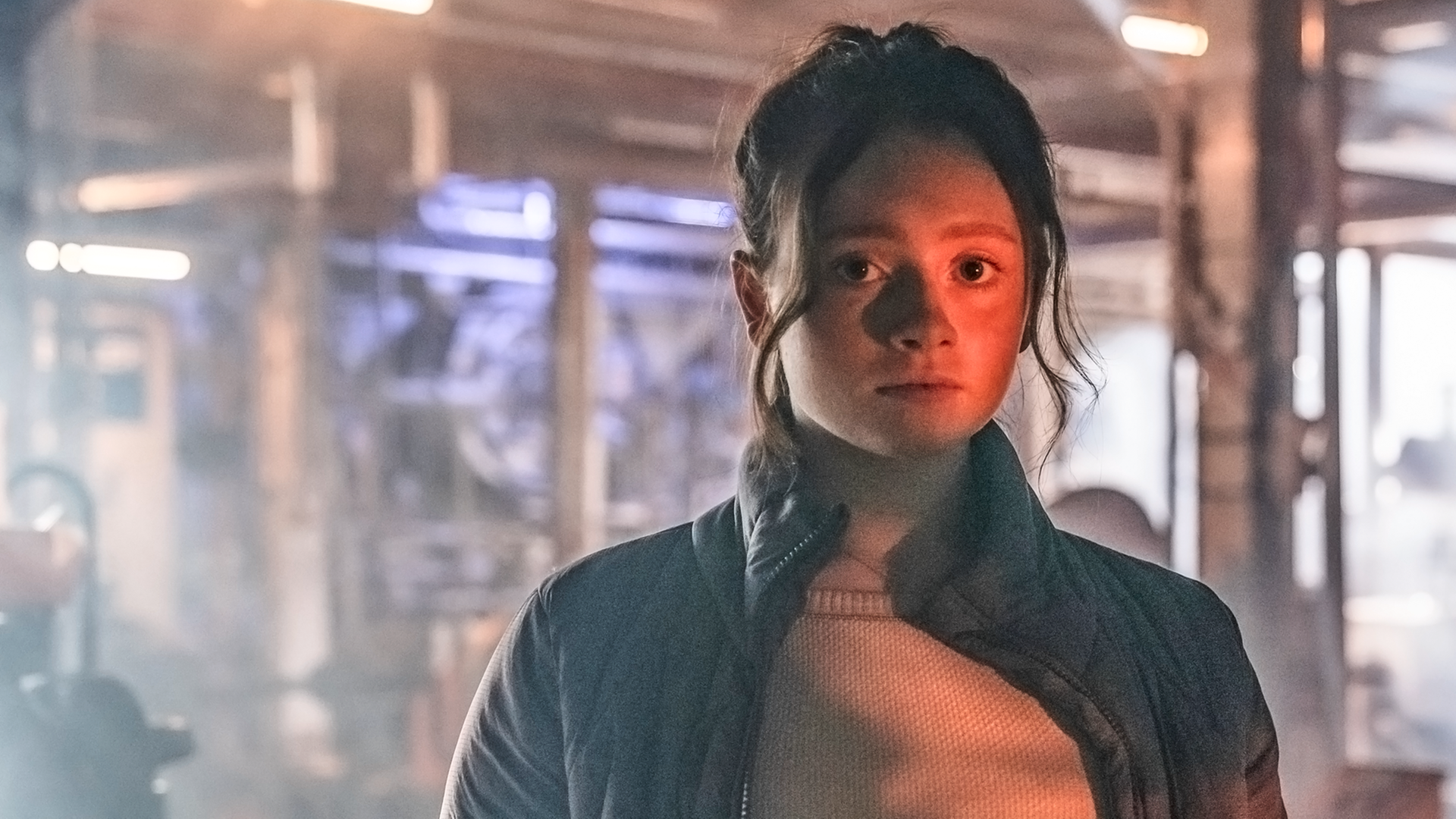 In einer großen Halle, in der eine riesige Plastikplane wie eine Wand gespannt ist: Bea schaut konzentriert nach vorne und hat eine Stoppuhr in ihrer linken Hand.