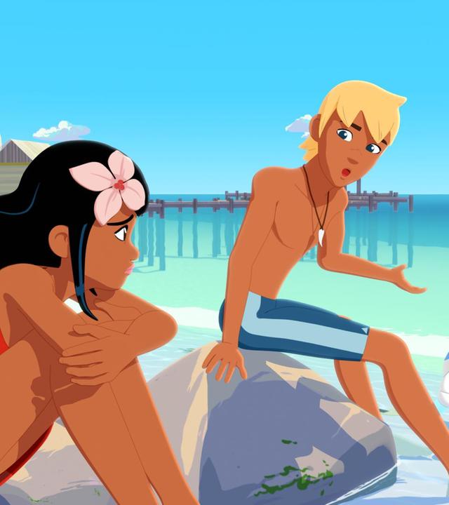 Timeti und Yann sitzen am Strand auf Steinen, die aus dem Wasser ragen. Vor ihnen im Wasser schwimmt Zoom. Hinter ihnen erstreckt sich die Bucht mit Bootsstegen und Hütten darauf. Yann spricht zu Timeti. Alle schauen einander ernst an.