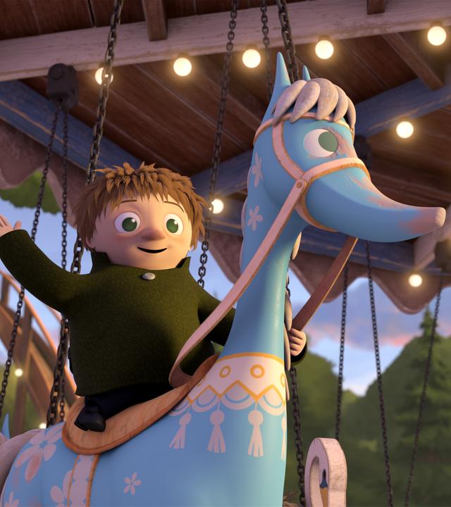 Toffel sitzt auf einem hellblauen Holzpferd eines Karussells und winkt fröhlich. Das Karussell ist mit Lichtern romantisch beleuchtet.