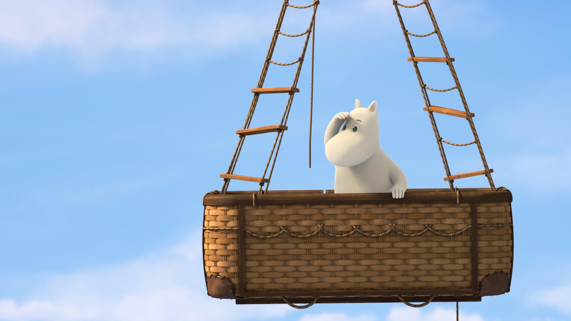 Hoch oben in den Lüften: Muminmama (Mitte) steht im Korb eines fliegenden Heißluftballons. Die Hand hält sie über die Augen und schaut ins Weite.