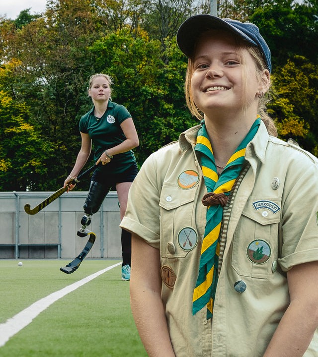 Collage: Annika steht rechts im Bild, trägt eine Pfadfinderuniform und lächelt in die Kamera. Mittig im Hintergrund ist sie auf einem Sportplatz zu sehen, wo sie sich mit Beinprothese und Schläger zum Schlag bereit macht.