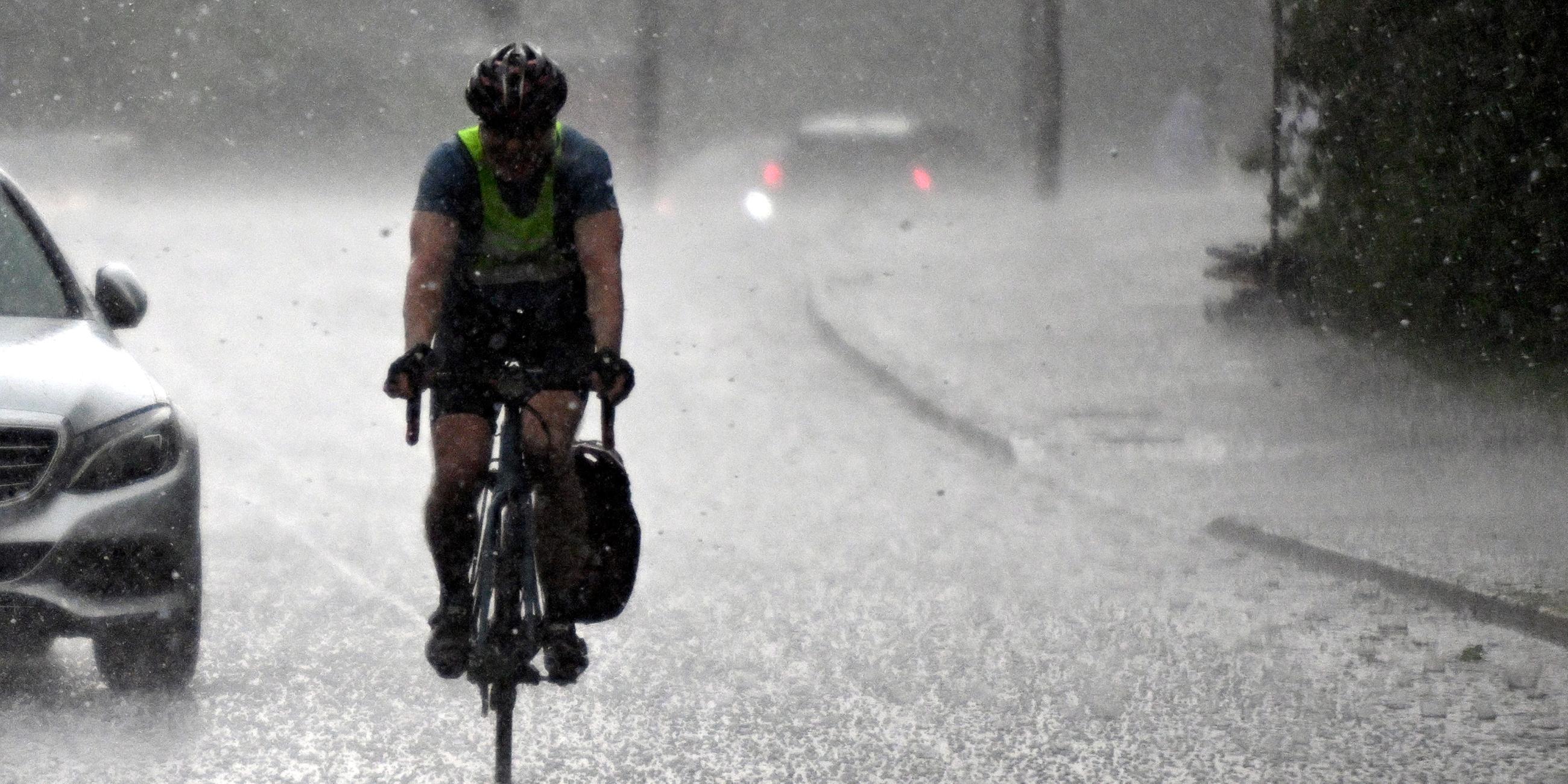 Ein Radfahrer fährt durch einen heftigen Regenschauer. 