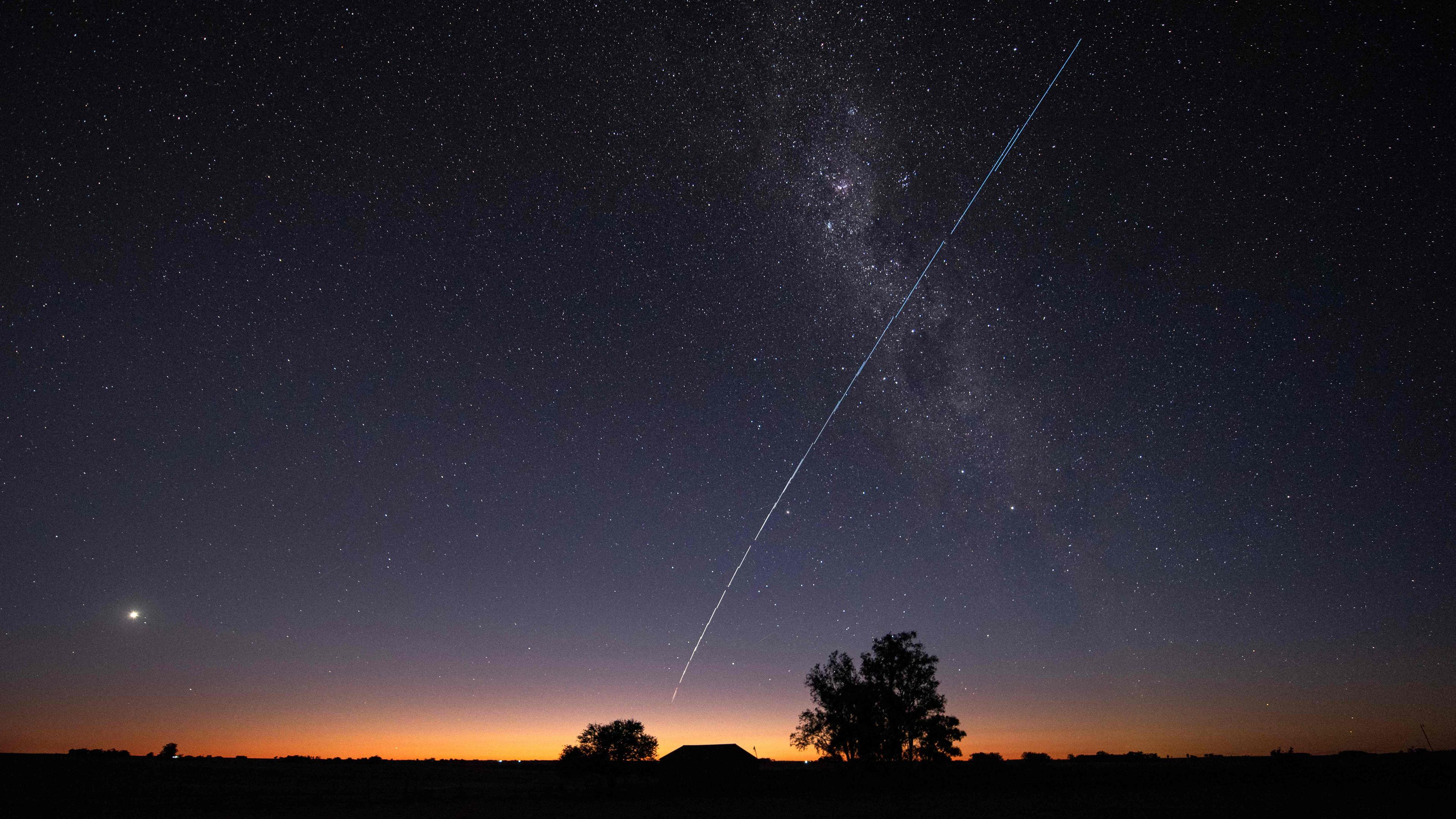 Dieses Langzeitbelichtungsbild zeigt eine Spur einer Gruppe von Starlink G6-27-Satelliten von SpaceX, die über Uruguay fliegen, mit einem Teil der Milchstraße und dem Planeten Venus (L) im Bild, aufgenommen am 12.11.2023