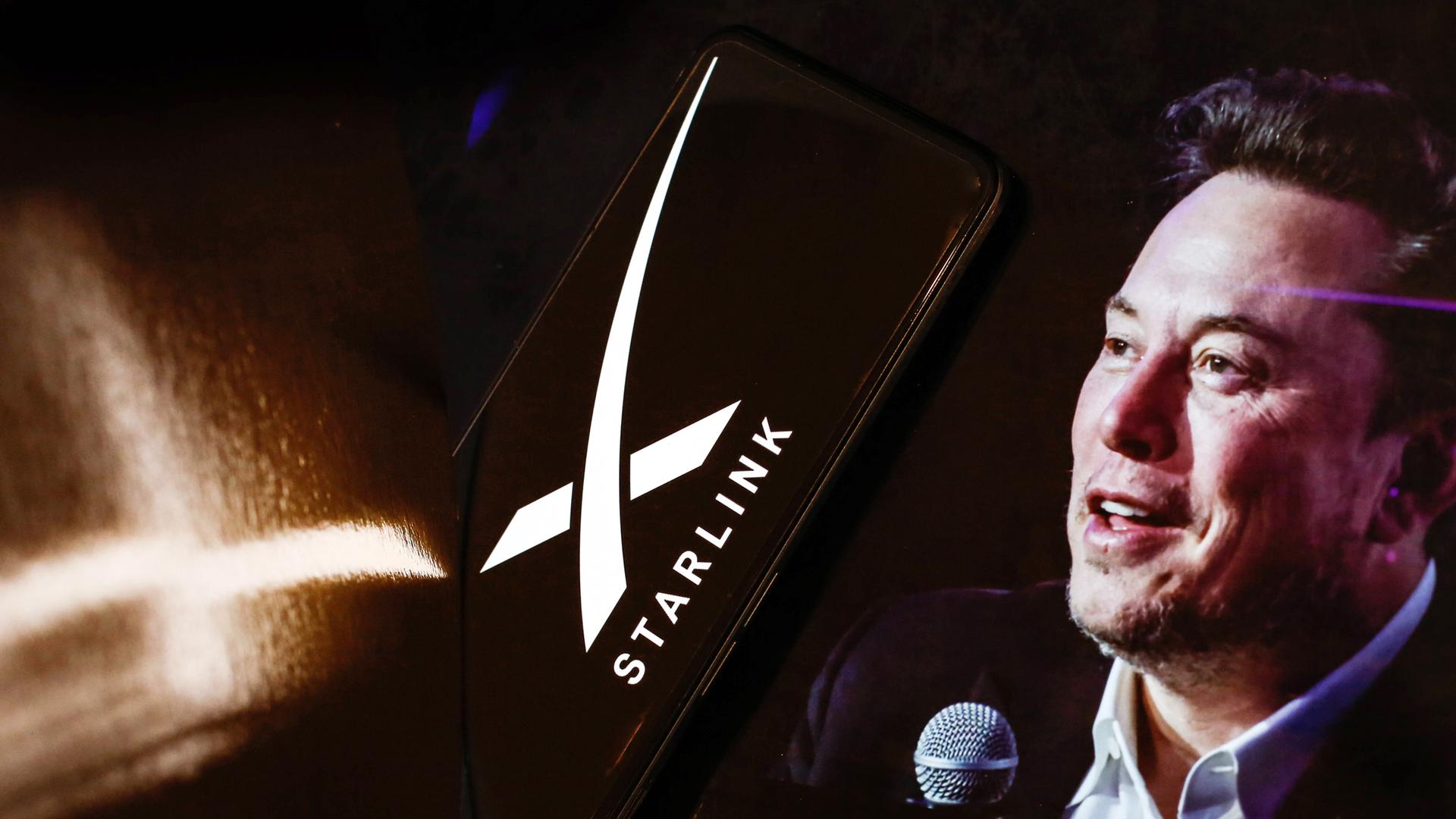 Ein Handy, auf dessen Bildschirm ein weißes X und das Wort "Starlink" zu sehen sind. Daneben ist das Gesicht eines Mannes (Elon Musk) mit dunklen Haaren und in einem Anzug zu sehen, der ein Mikrofon in der Hand hält.