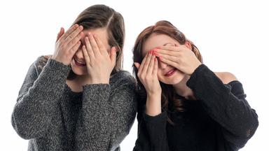 Zwei Mädchen halten sich die Augen zu