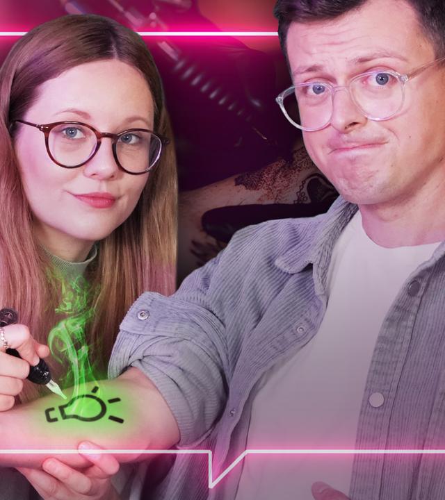 Beide blicken zur Kamera. Jacob sieht sorgenvoll aus. Auf seinem rechten Arm ist das Logo heureka im Stil eines Tattoos zu sehen.