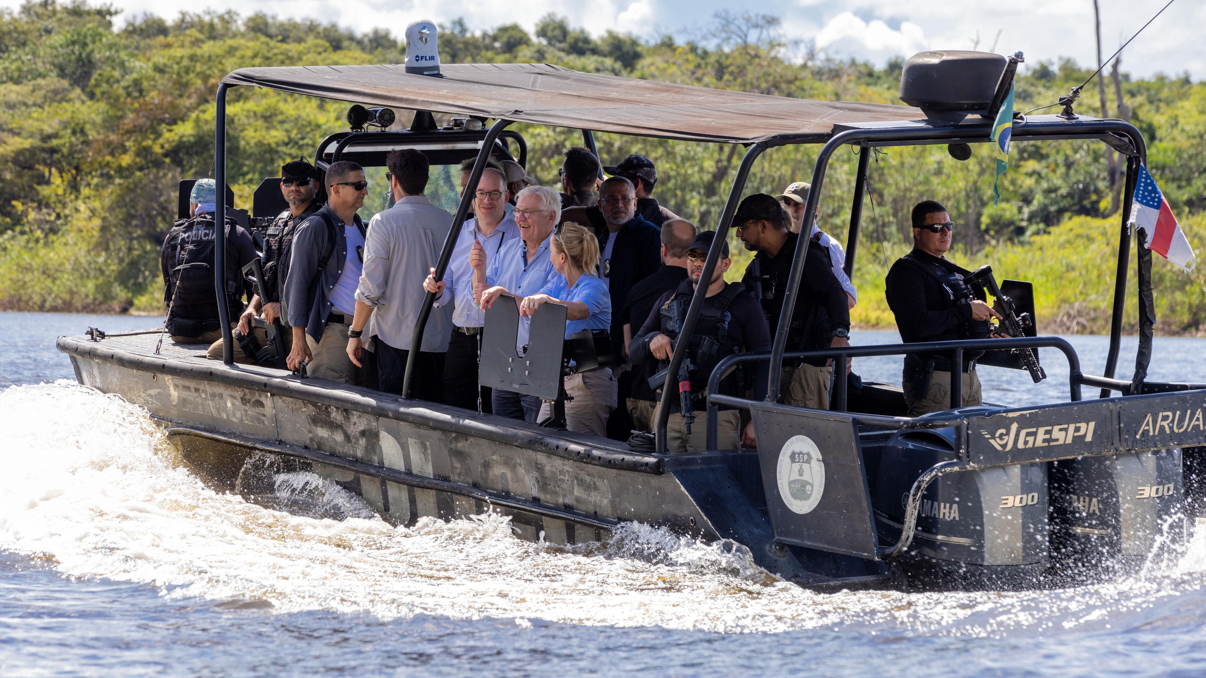 Bundespräsident Frank-Walter Steinmeier fährt mit Mitgliedern seiner Delegation mit einem Boot auf einem Fluss durch den Regenwald.