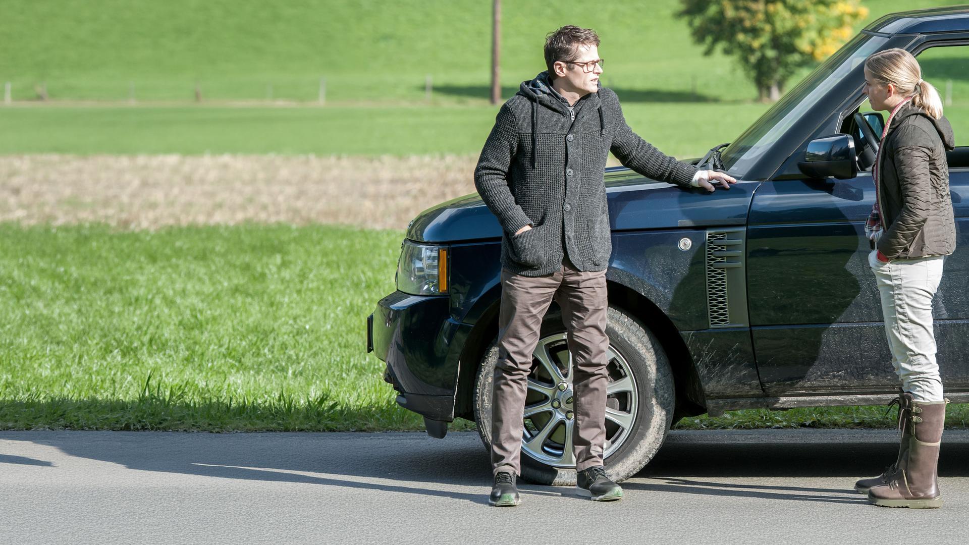 "Der Bergdoktor - Sternenhimmel (2)": Thomas Mannfeld (Roman Knižka) und Lisa Unger (Merle Collet) stehen sich mit einigem Abstand vor einem Auto gegenüber.