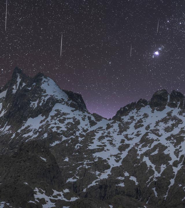 Sternschnuppen am  Nachthimmel über einem Gebirge.