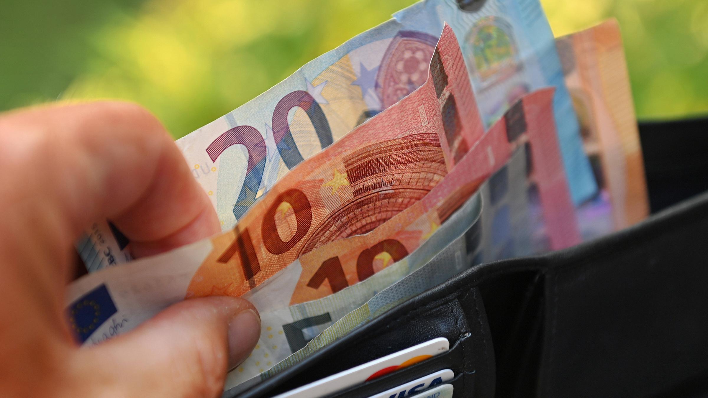 Archiv: Eine Hand nimmt Euro Scheine aus einem Portemonnaie