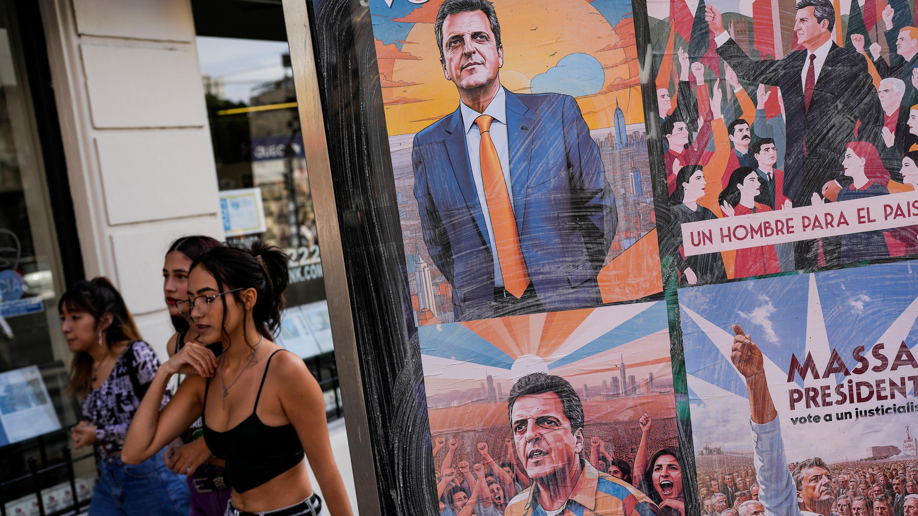 Argentinien, Buenos Aires: Fußgänger gehen an Wahlkampfplakaten vorbei, die für Wirtschaftsminister Sergio Massa, den Kandidaten der Regierungspartei, werben.