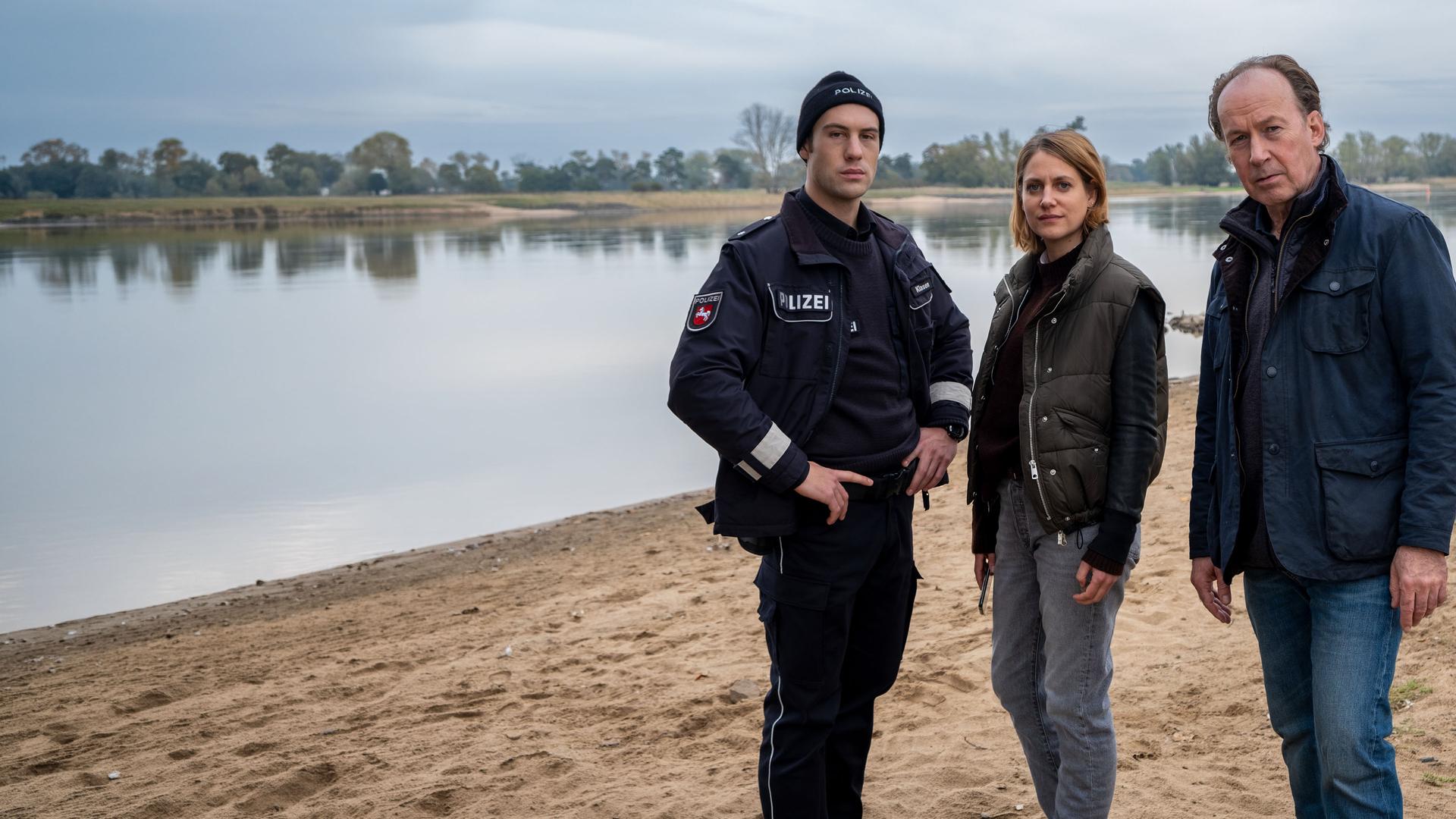 "Wendland - Stiller und das große Schweigen": Oliver Klasen (Malte Thomsen), Kira Engelmann (Bettina Burchard) und Jakob Stiller (Ulrich Noethen) stehen zusammen am Ufer.