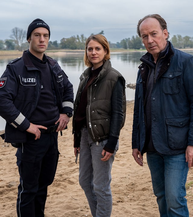 "Wendland - Stiller und das große Schweigen": Oliver Klasen (Malte Thomsen), Kira Engelmann (Bettina Burchard) und Jakob Stiller (Ulrich Noethen) stehen zusammen am Ufer.