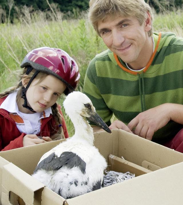 Fritz und zwei Kinder kümmern sich um einen jungen Storch.
